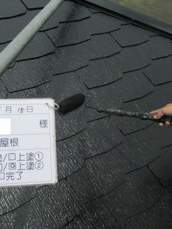 屋根をローラーで塗っている